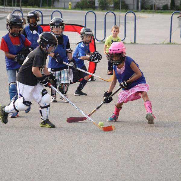 Children playing ball hockey outdoors.