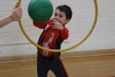 Child throwing basketball through hoop.