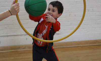 Child throwing basketball through hoop.