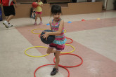 Girl jumping over hoops with basketball.