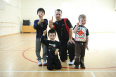 Happy kids and coach giving thumbs-up to multi-sport class.