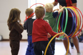 Kids grabbing hoops from coach during Sportball multi-sport class.