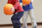 Two happy boys holding volleyballs during Sportball multi-sport class.