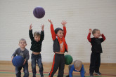 Happy kids throwing balls in the air during Sportball multi-sport class.