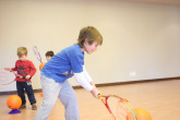 Boy lining up ball to hit with tennis racquet.