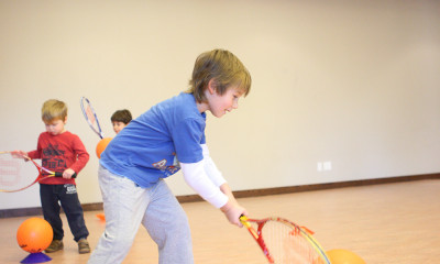 Boy lining up ball to hit with tennis racquet.