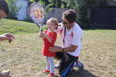 Sportball Coach helping girl with tennis racquet.