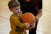 Sportball coach showing boy how to hold volleyball.