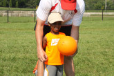 Sportball coach showing boy how to hold volleyball.